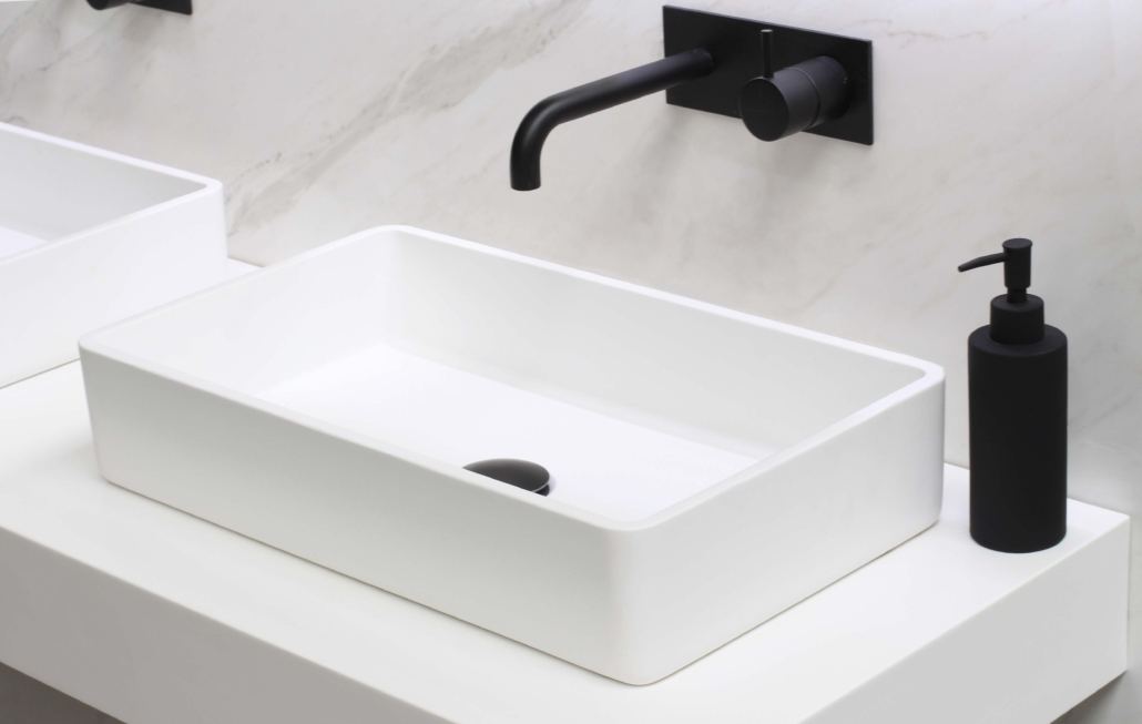 Moderne, hvit vask på baderom med svarte detaljer og svart såpebeholder.